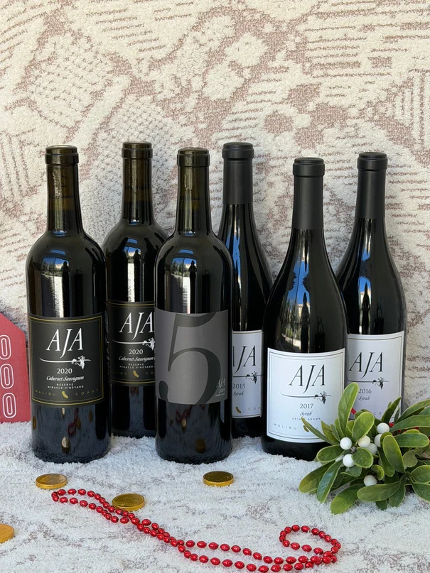 Six bottles of AJA estate red wine on a holiday blanket